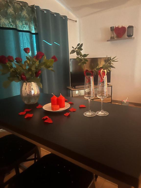 ベス・シュル・イソルにあるPetit Paradisの2つのワイングラスと赤いバラが置かれたテーブル
