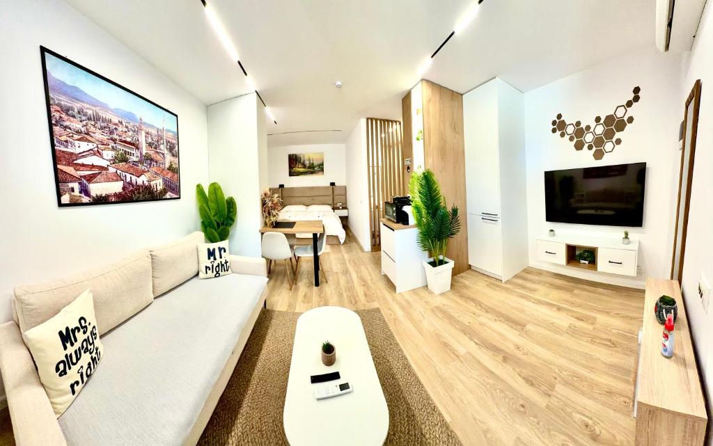 a living room with a white couch and a tv at Lois Apartment in Tirana