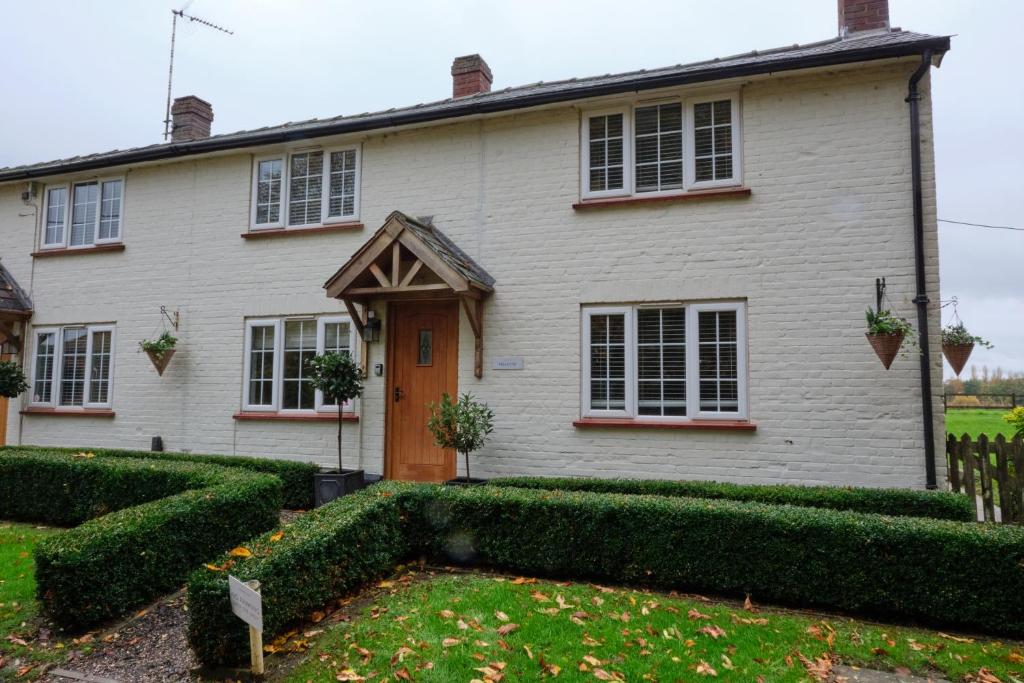 a white house with hedges in front of it at The Granary Cottages 