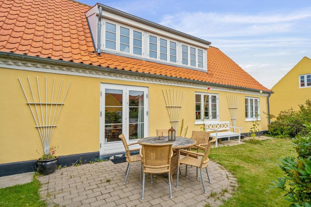a table and chairs in front of a yellow house at Stort byhus i centrum af Skagen in Skagen