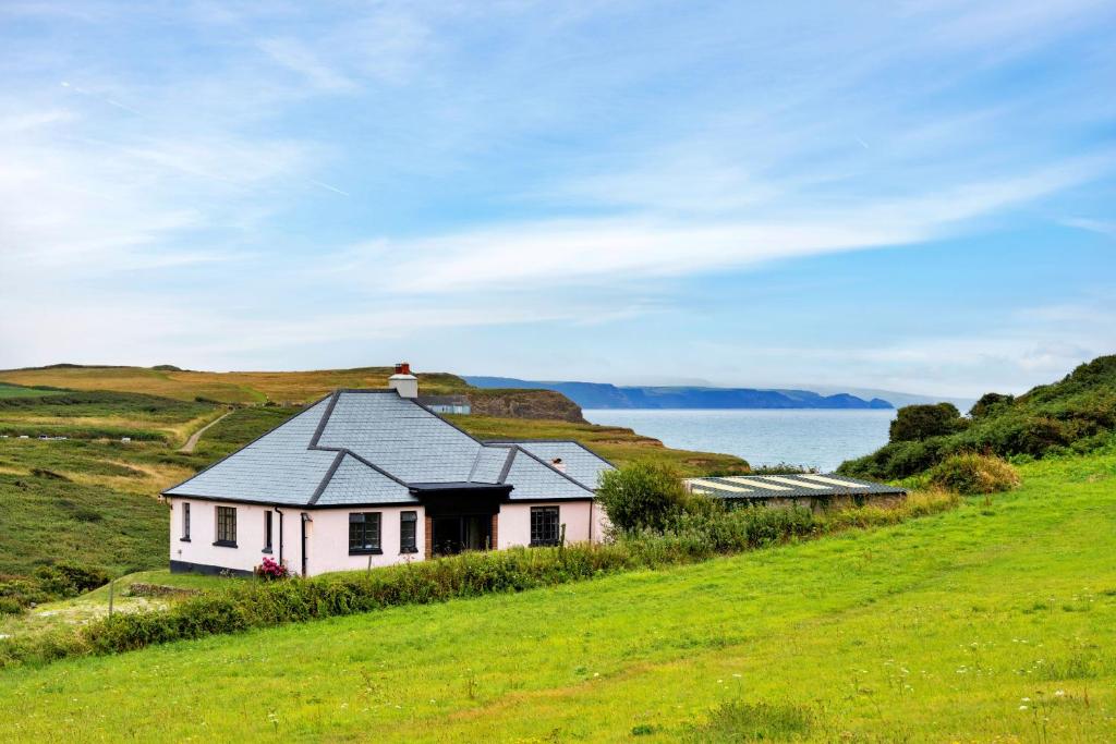 a house on a hill with the ocean in the background at Finest Retreats - The Breakers in Poughill