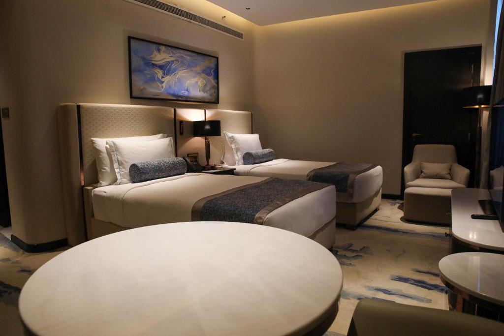 a hotel room with two beds and a table at Century Marina Hotel - Lusail in Lusail