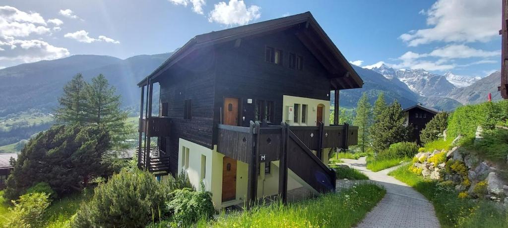 une maison sur une colline avec des montagnes en arrière-plan dans l'établissement Ferienwohnung Aragon M88, à Ernen