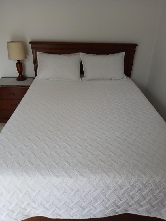 a large white bed with a wooden headboard and pillows at Tu Estancia en Cali - Valle del Lili in Cali