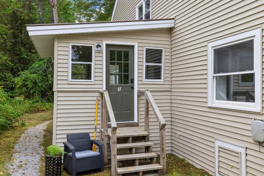 a tiny house with a green door and stairs at Comfy Large Bungalow - 4 Bed 1BA On Private Pond in Bradford