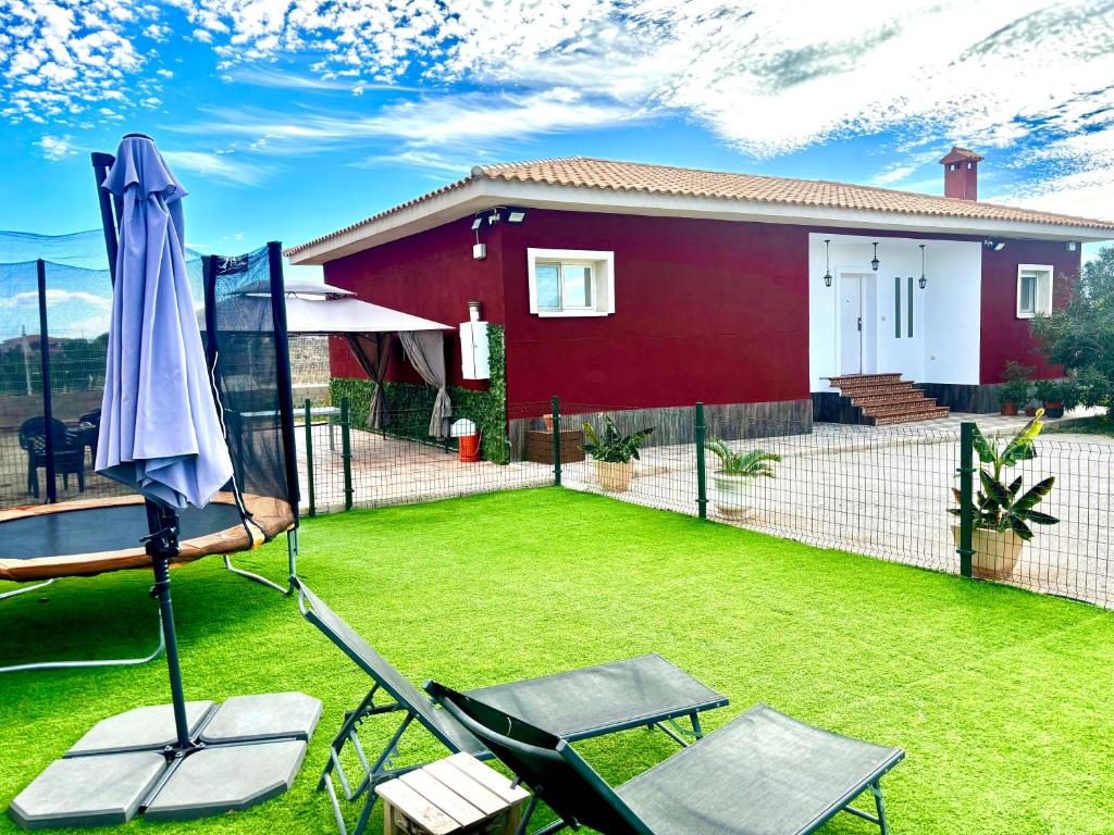 a yard with an umbrella and chairs and a house at --CHALET EN ALICANTE-- Piscina Privada in Moralet