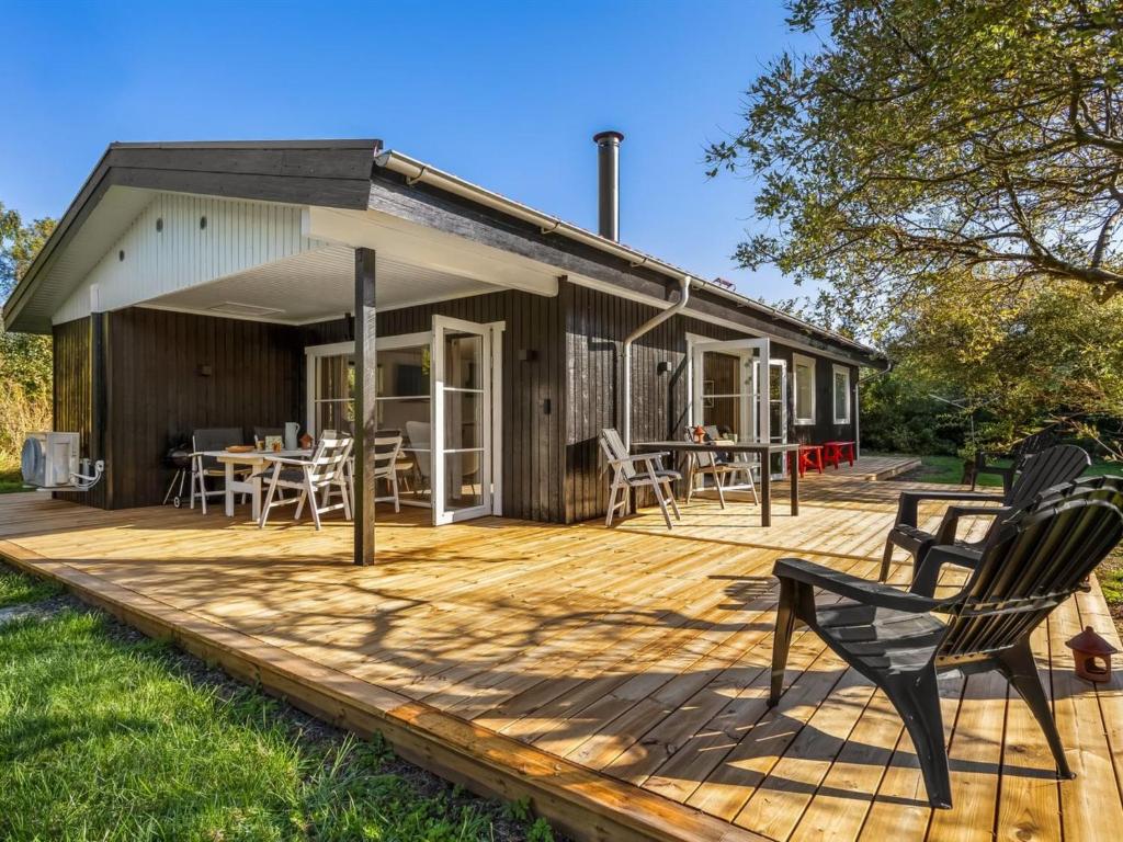 a wooden deck with chairs and a house at Holiday Home Tameran - 1km from the sea by Interhome in Gedesby