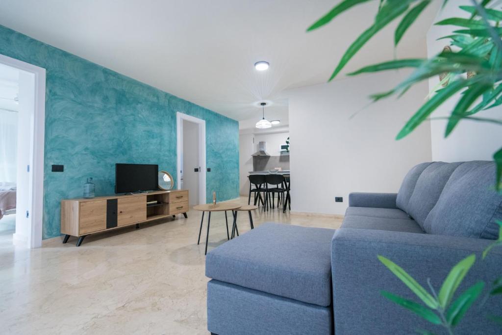 Una sala de estar con un sofá azul y una mesa. en Apartamentos Maresía by Infinity Summer, en Las Palmas de Gran Canaria
