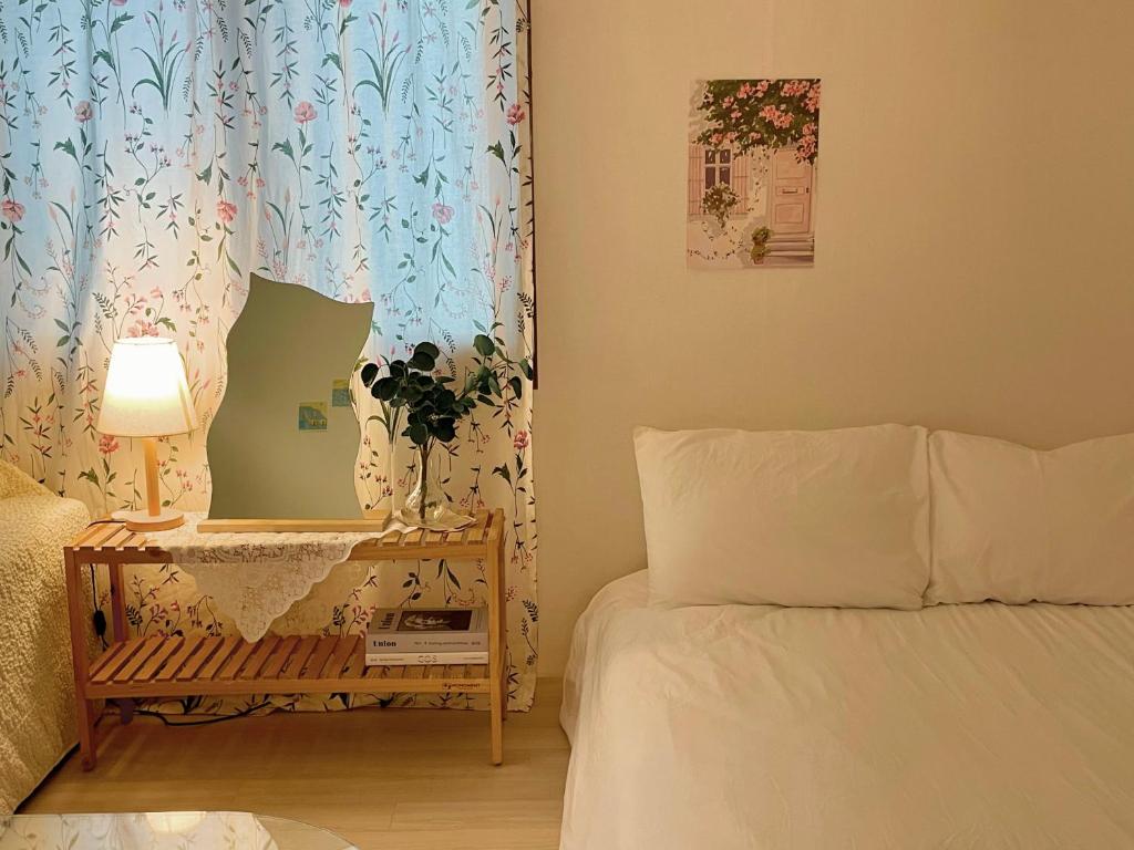 ein Schlafzimmer mit einem Bett und einem Tisch mit einer Lampe in der Unterkunft sentimental in Busan