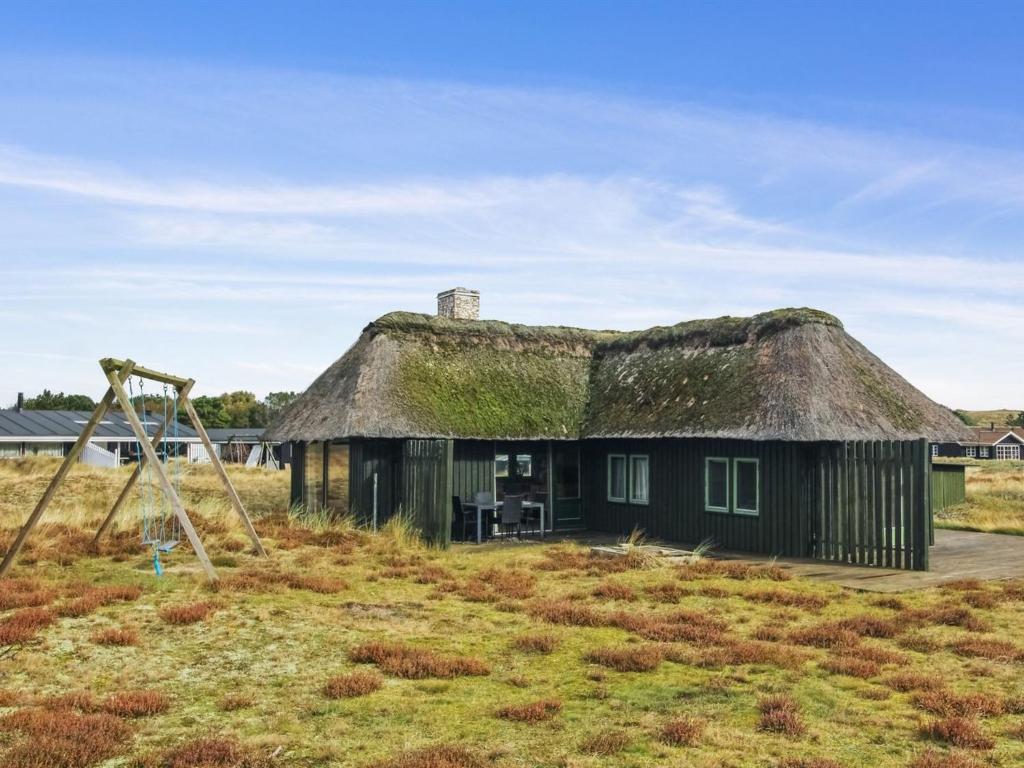 an old house with a thatched roof and a swing at Holiday Home Asel - 1km from the sea by Interhome in Sønderho