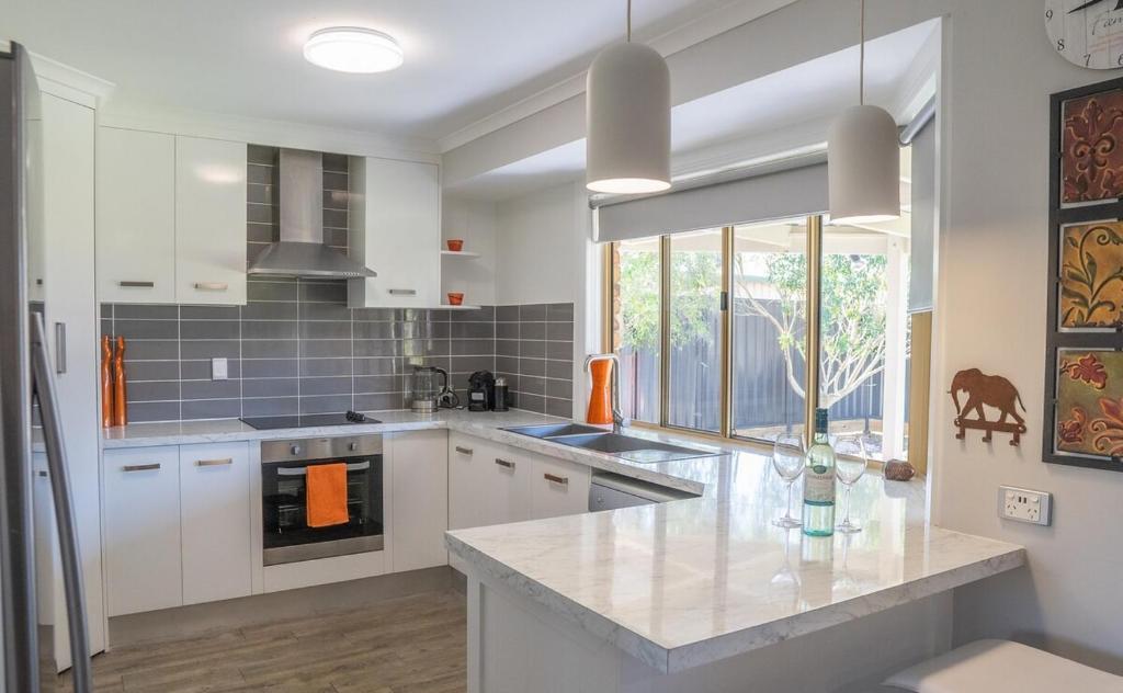 Una cocina con gabinetes blancos y encimera. en Stays with Ripley 3 min to hospital and beach Pet friendly, en Urraween