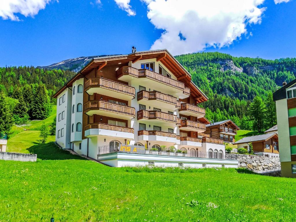 a large building on a hill with a green field at Apartment A11 by Interhome in Leukerbad