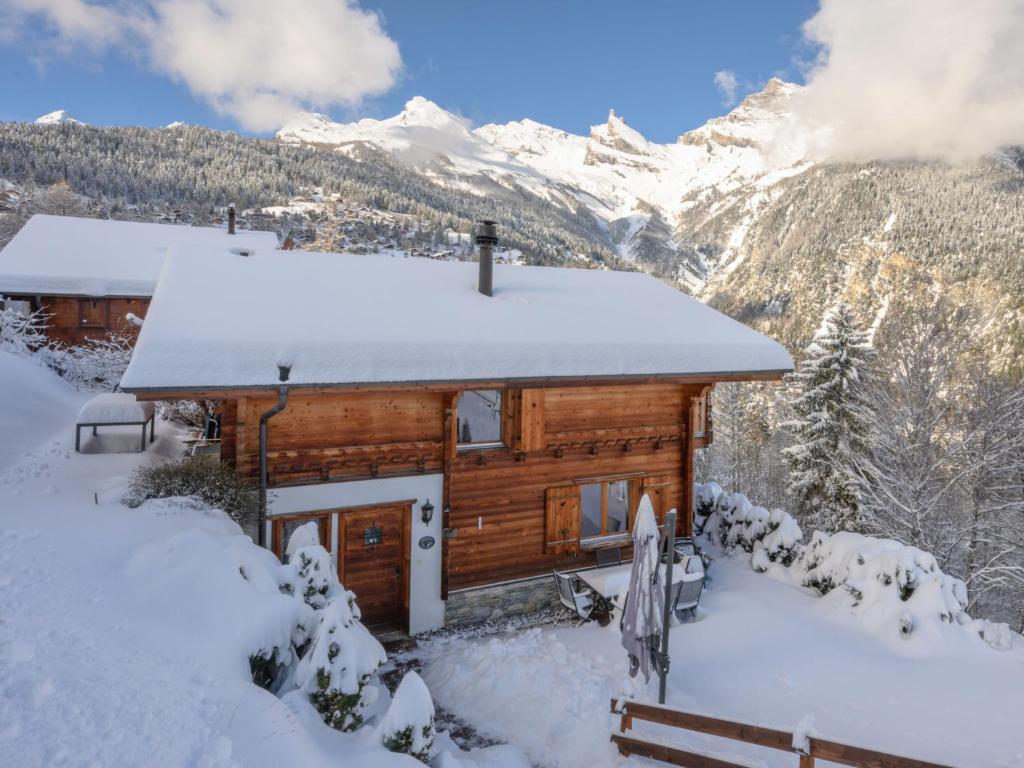 una cabaña de madera en la nieve con montañas en el fondo en Chalet Ecureuil noir by Interhome, en Ovronnaz
