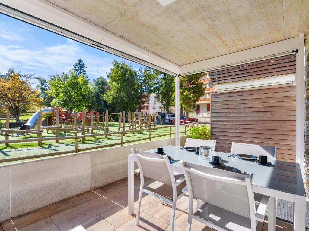 a patio with a table and chairs and a playground at Apartment Central Parc 2 by Interhome in Crans-Montana