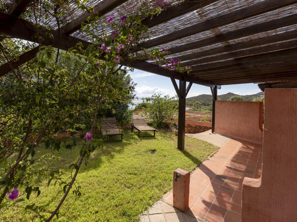 einen Garten mit Bänken und einer hölzernen Pergola in der Unterkunft Holiday Home Villa 20 by Interhome in SantʼAmanza