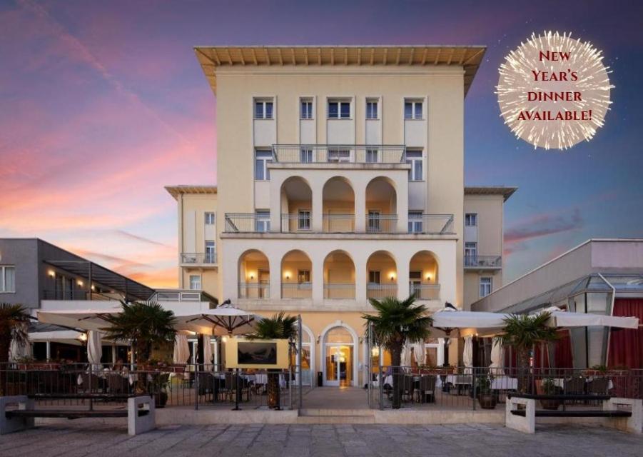 a large white building with palm trees in front of it at BO Hotel Palazzo in Poreč