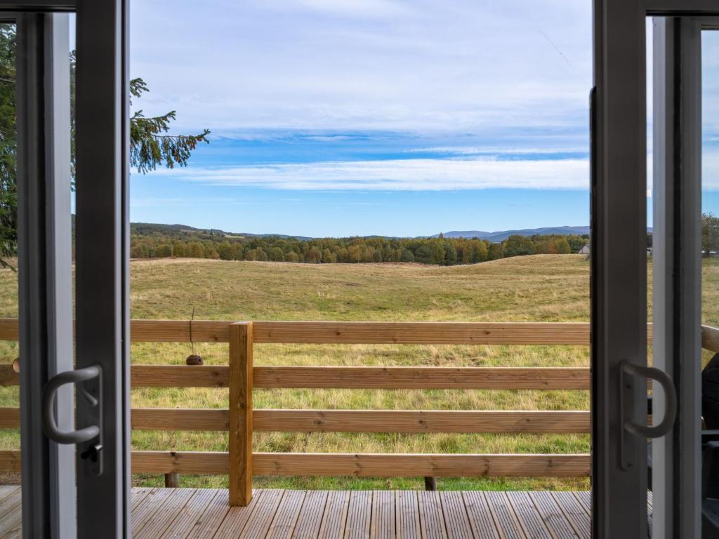 a door to a porch with a view of a field at Chalet Lodge 15 by Interhome in Boat of Garten