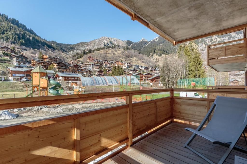 a chair sitting on a balcony with a view of a town at Blanchets, Terrasse et confort 4 étoiles in Champagny-en-Vanoise