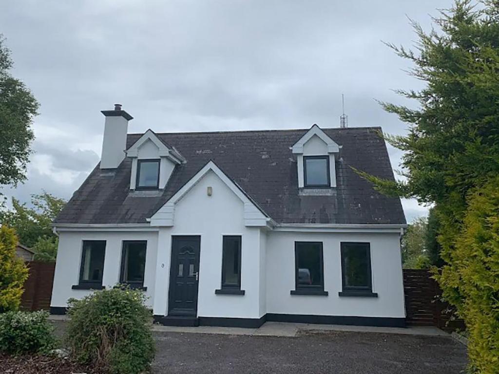 a white house with a black roof at Holiday Home Burren Seaside Lodge by Interhome in Ballyvaughan