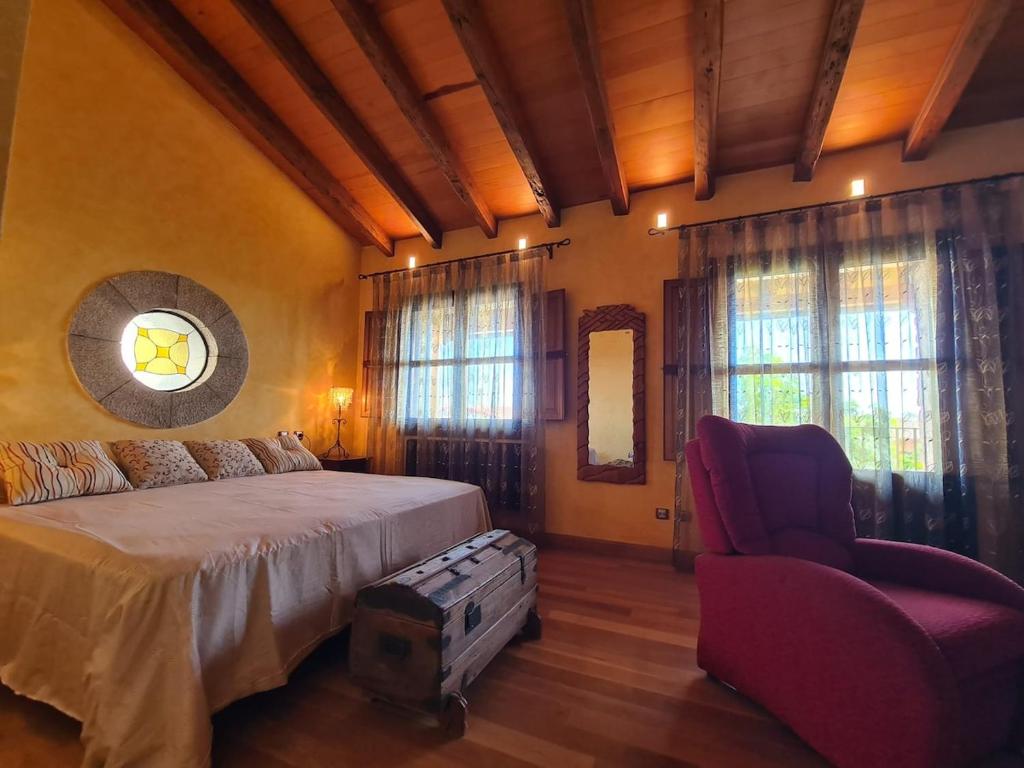 a bedroom with a bed and a chair and windows at Tu Capricho in Piedralaves