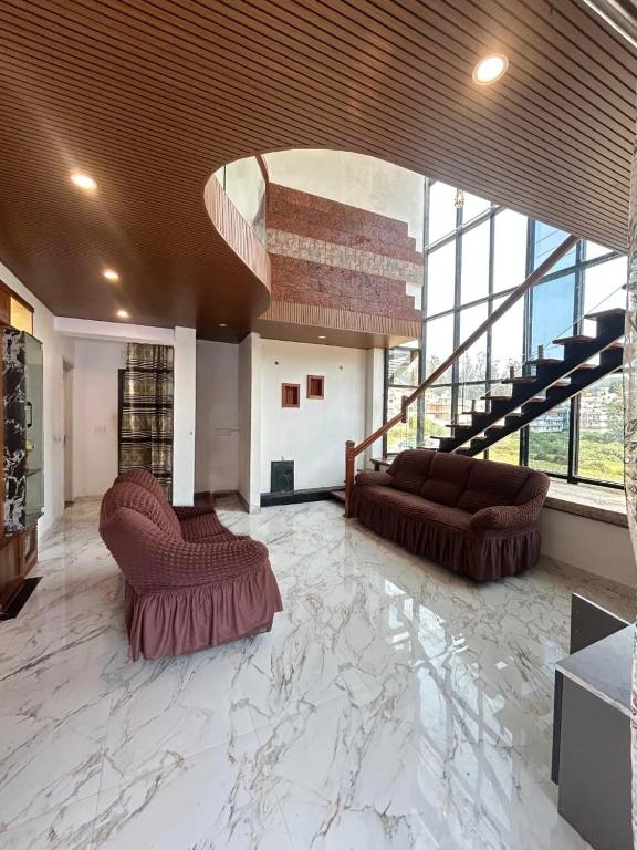 una gran sala de estar con 2 sofás y una escalera. en Zarax home stay, en Ooty