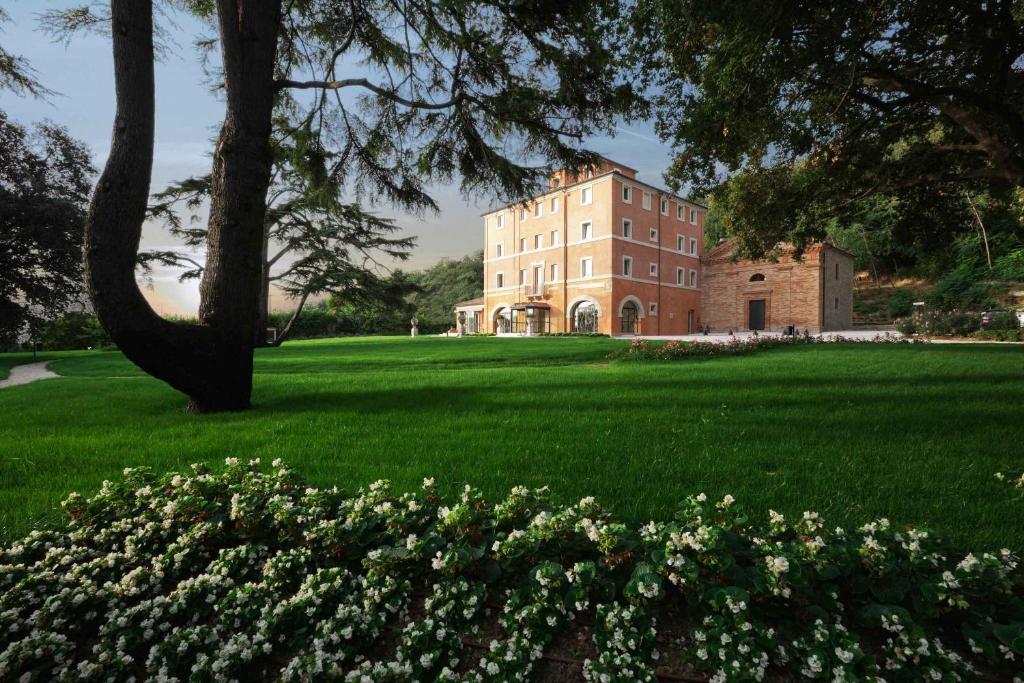 un grand bâtiment sur un champ verdoyant et luxuriant avec des fleurs dans l'établissement Villa Lattanzi, à Marina Palmense