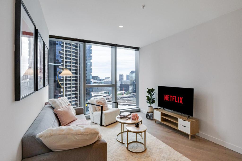 a living room with a couch and a tv at CBD Elegant 2BR Apt with Pool, Gym & City Views in Melbourne