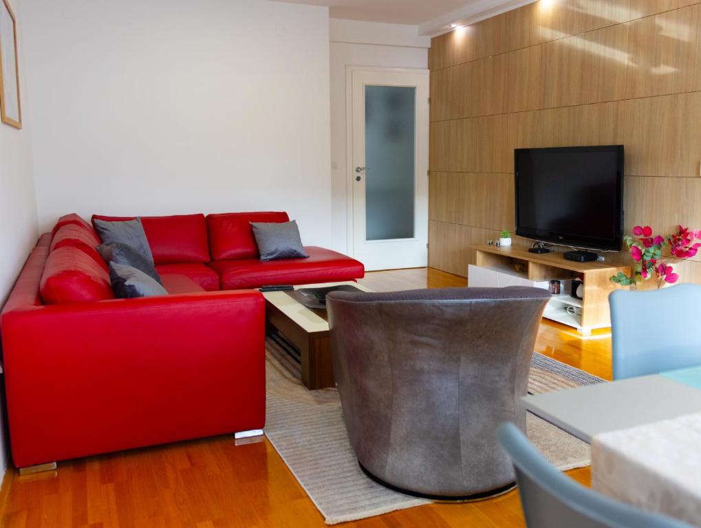 a living room with a red couch and a tv at VerdeLuxe Sarajevo in Sarajevo