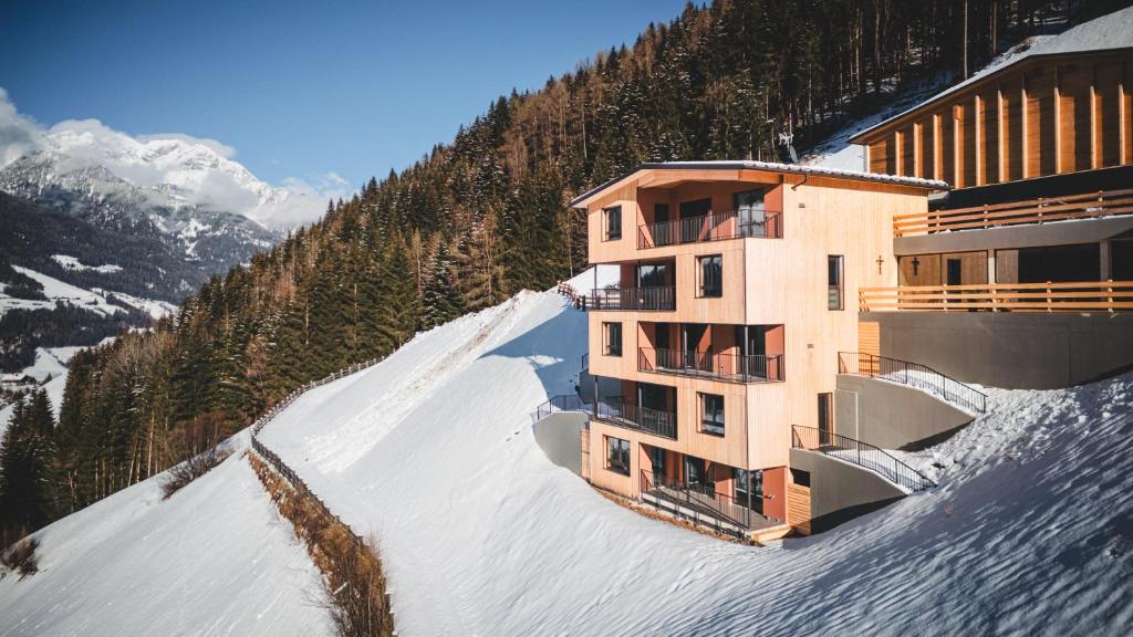 a building on the side of a snow covered mountain at Lahnerhof Chalets in Lutago