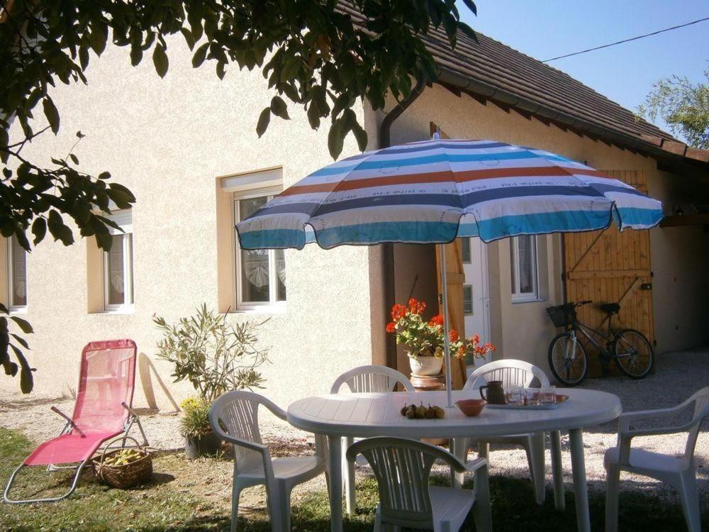 a table and chairs with an umbrella in front of a house at Gite Du Randonneur in Sennecey-le-Grand