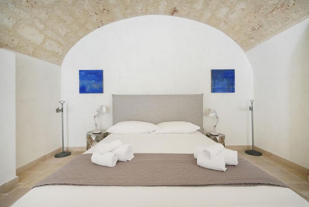 a white bedroom with a large bed with two pillows at Palazzo Della Tore 001-Elegant Historic Escape in Torre a Mare
