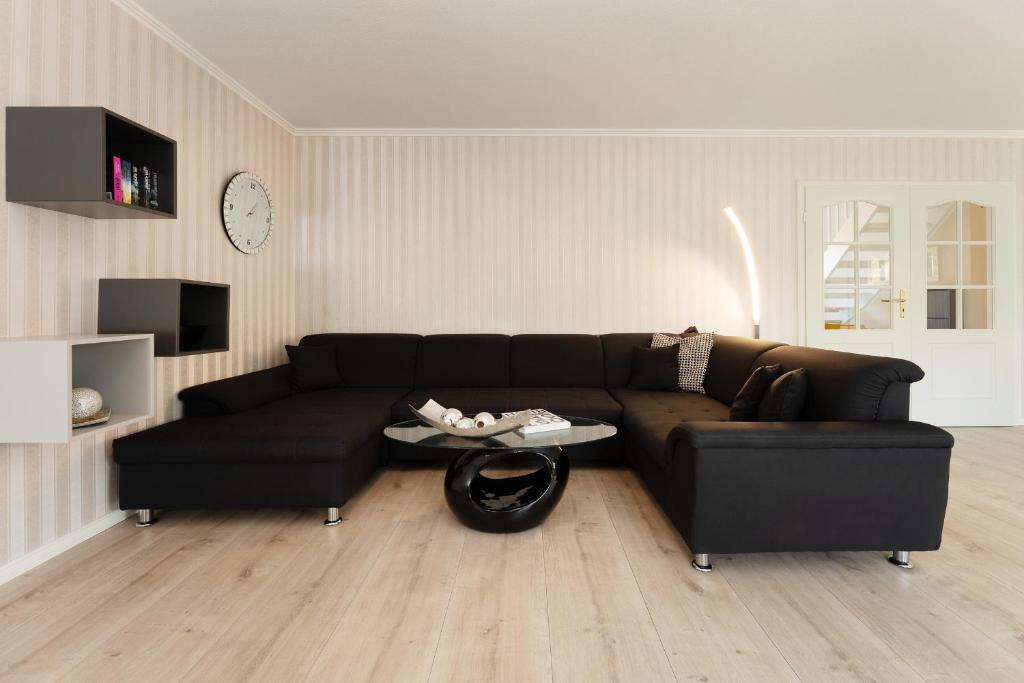 ブルク・アウフ・フェーマルンにあるFerienhaus Wohlerの黒いソファとテーブルのあるリビングルーム