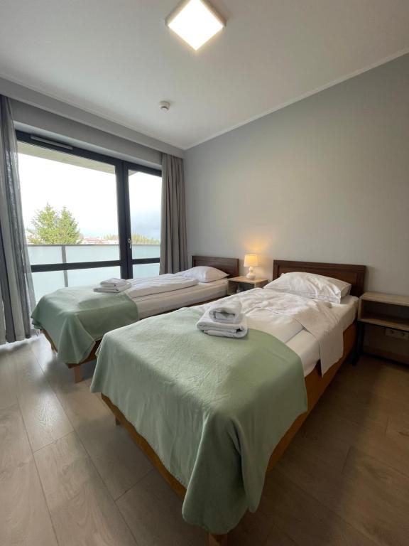 two beds in a room with a large window at Triventi Apartament 2 sypialnie, garaż, blisko Tropikana i wyciąg na Kopę in Karpacz