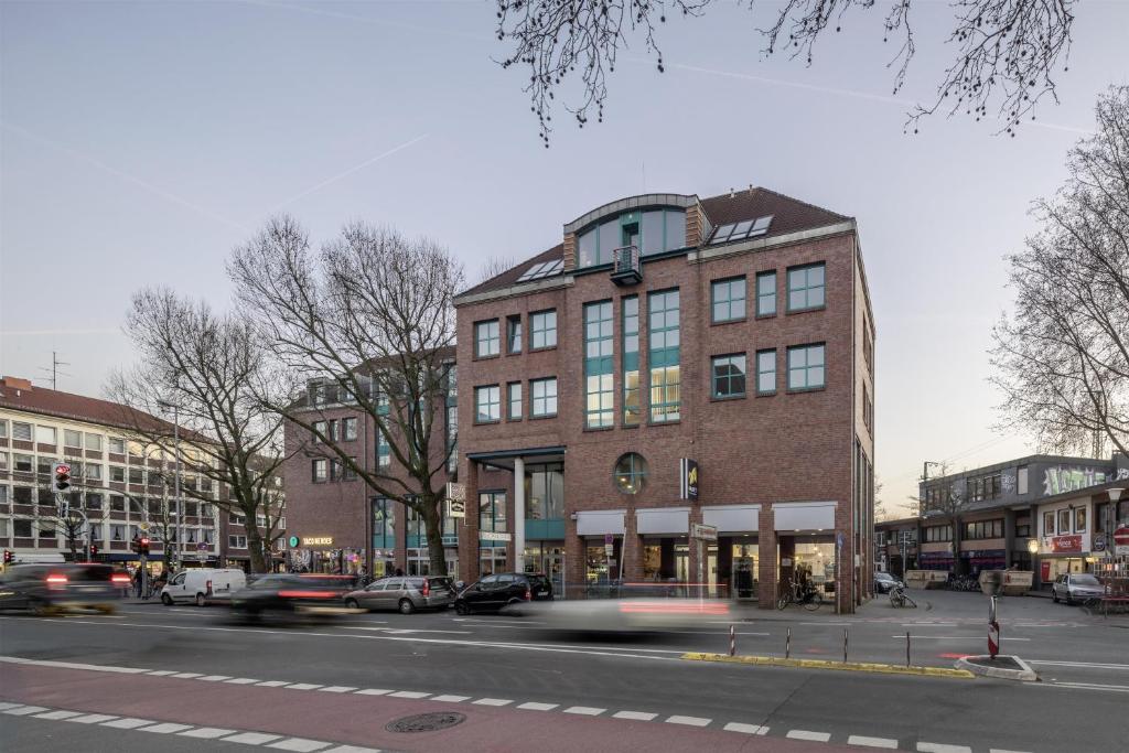 a large brick building on a city street with cars at Flowers Hotel Münster in Münster