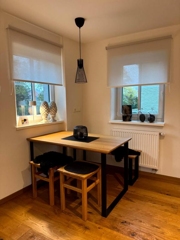 a kitchen with a wooden table and two windows at Modernes Häusle in Segnitz I Main & Wein in Segnitz