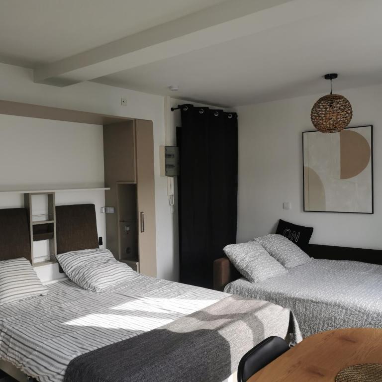 a room with two beds and a wooden table at Belle étape Honfleuraise in Honfleur