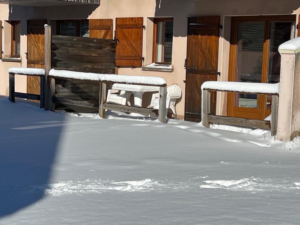 a snow covered yard with a bench and a house at Super Besse chez Sophie 2ch, séjour, wifi, 2tv, rdc, terrasse, parc, piscine, pkg in Besse-et-Saint-Anastaise