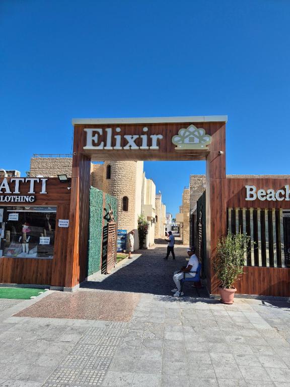 una persona sentada en una silla debajo de la entrada de un edificio en Elixir Hotel Hurghada, en Hurghada