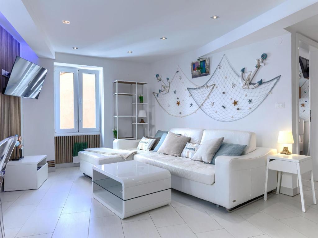 Sala de estar blanca con sofá blanco y mesas en Apartment Ambient by Interhome, en Rovinj