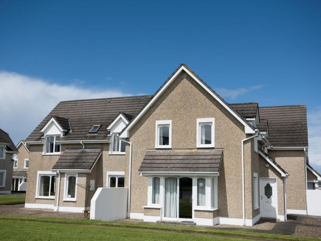 a brick house with white windows and a roof at Holiday Home Moore Bay - TR4 HH No 14A by Interhome in Kilkee