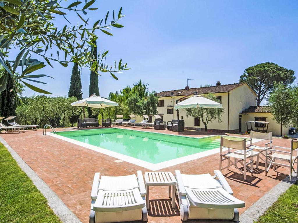 a pool with chairs and umbrellas next to a house at Villa Villa Beboli per 18 pax by Interhome in Lamporecchio