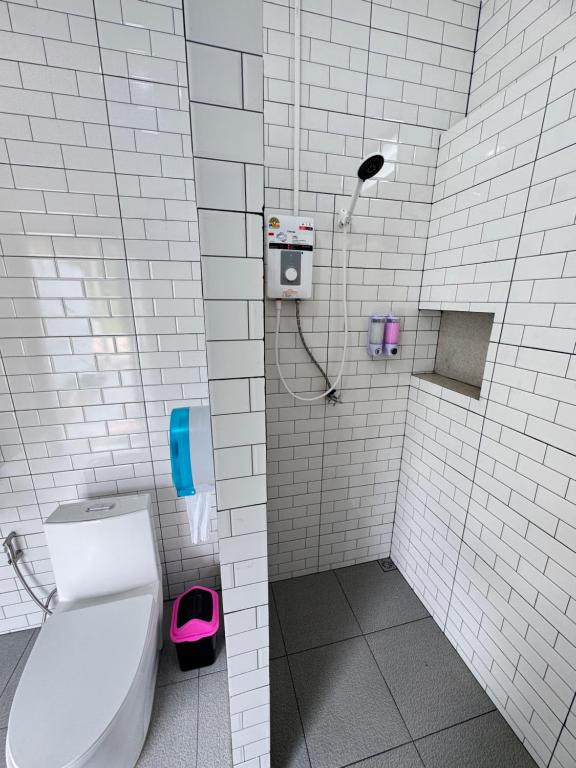 a white tiled bathroom with a toilet and a shower at Seaview phuwamin in Phra Ae beach