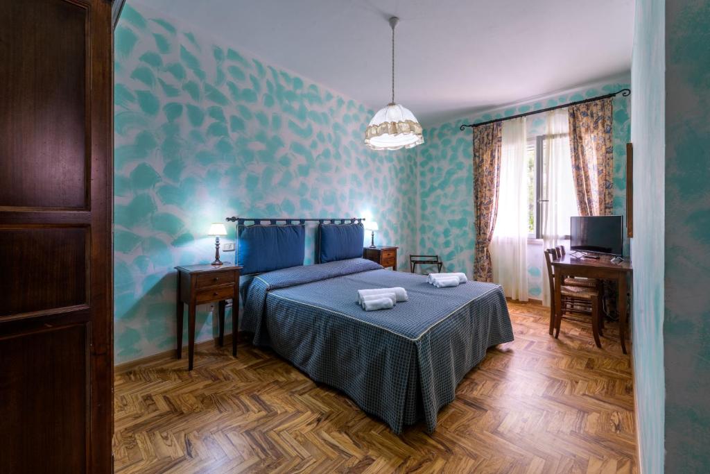 a bedroom with a bed with blue walls and a desk at Hotel Residence I Briganti di Capalbio in Capalbio