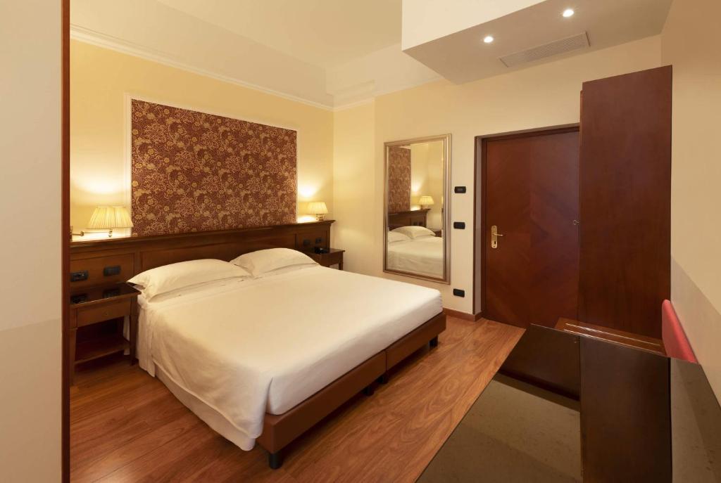a bedroom with a large white bed and a mirror at Lancaster Hotel in Milan