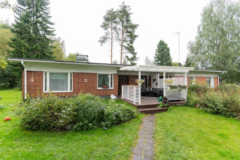 a small brick house with a porch on a yard at Rovaniemi Spacious Lapland Vacation Home with Private Sauna & Lappish Fire Hut in Rovaniemi