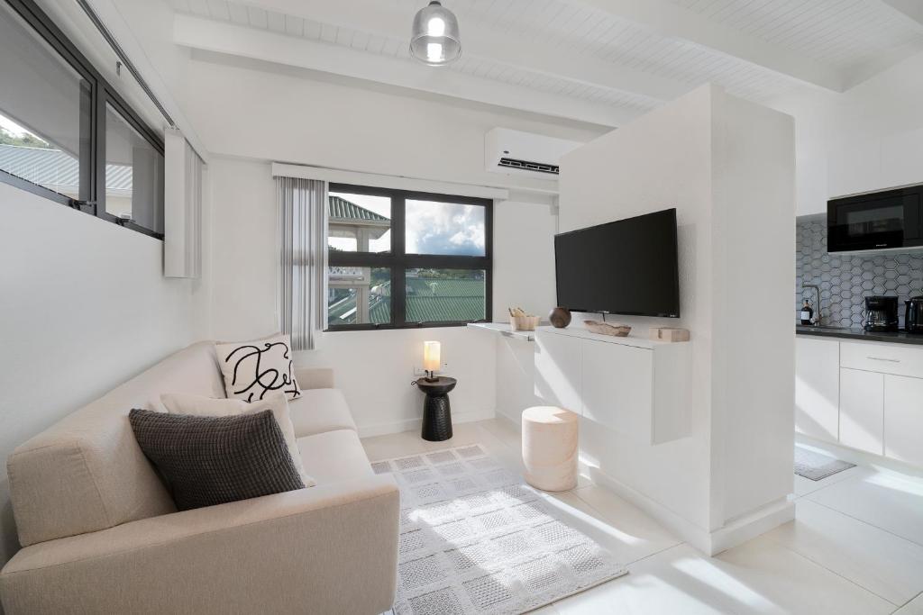a white living room with a couch and a tv at Atrium Apartments - Cocoa Villa in Grand Anse