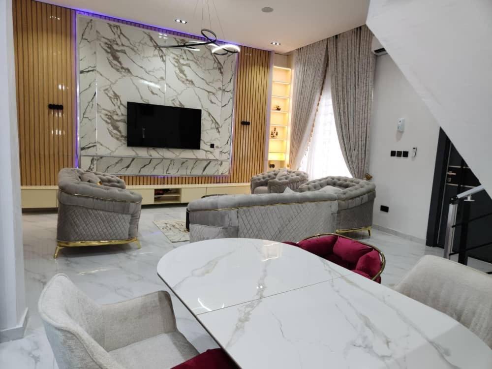 Una sala de estar con una mesa y sillas y un televisor. en LPMD Apartment, en Ikuata