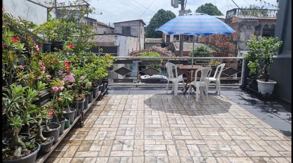 une terrasse avec un parasol, des chaises et des plantes en pot dans l'établissement Casa família COP30, à Belém
