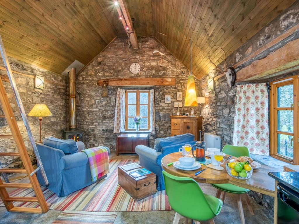 a living room with a table and blue chairs at Holiday Home The Romantic Bothy by Interhome in Invermoriston
