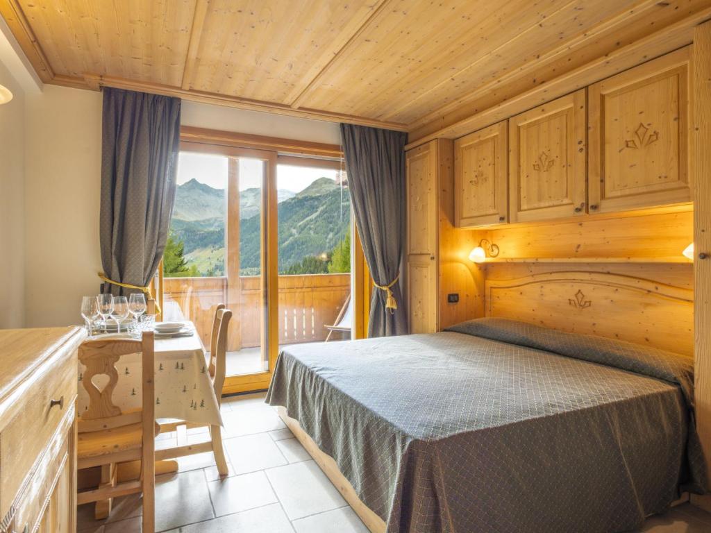 a bedroom with a bed and a balcony with mountains at Apartment Residence gli Scoiattoli-2 by Interhome in Madesimo